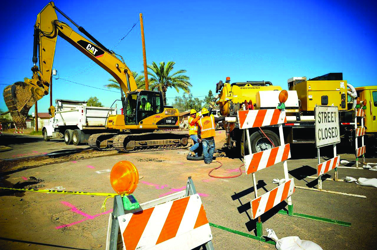 Image of street closed sign with construction equipment ni the background